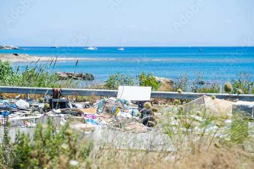 Road and footpath full of garbage with a view of the sea.