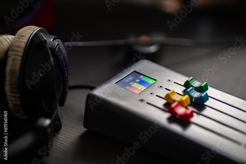 Daytime photo of a grey music studio desk with music production setup and colorful faders. 