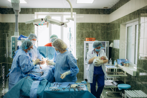 surgeons perfoming surgery operation of abdominal cesarean section during child delivery birth at clinic operating room. photo