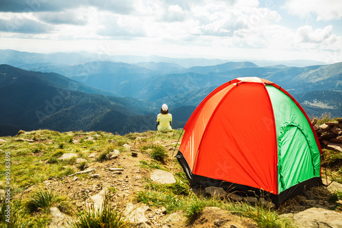 Woman with a tent on top of a mountain