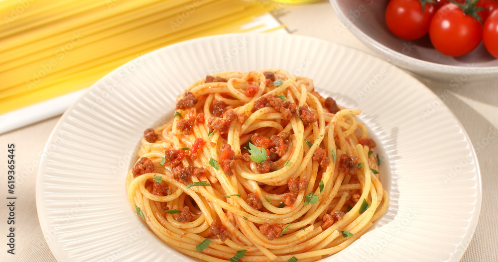spaghetti bolognese on plate. italian pasta with meat sauce on a light background with tomato, raw spaghetti and olive oil. dish of mediterranean cuisine. food on the table on a sunny day. spaghetti bolognese on plate. italian pasta with meat sauce on a light background with tomato, raw spaghetti and olive oil. dish of mediterranean cuisine. food on the table on a sunny day.