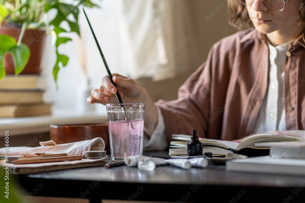 Artist paints with acrylic clean brush in transparent glass of water