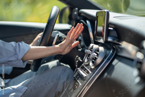 Female hand checks flow of cold air from air conditioner inside car. Woman driver suffer from heat in vehicle holding hand at conditioning system cooling grid. Hot summer season and driving automobile