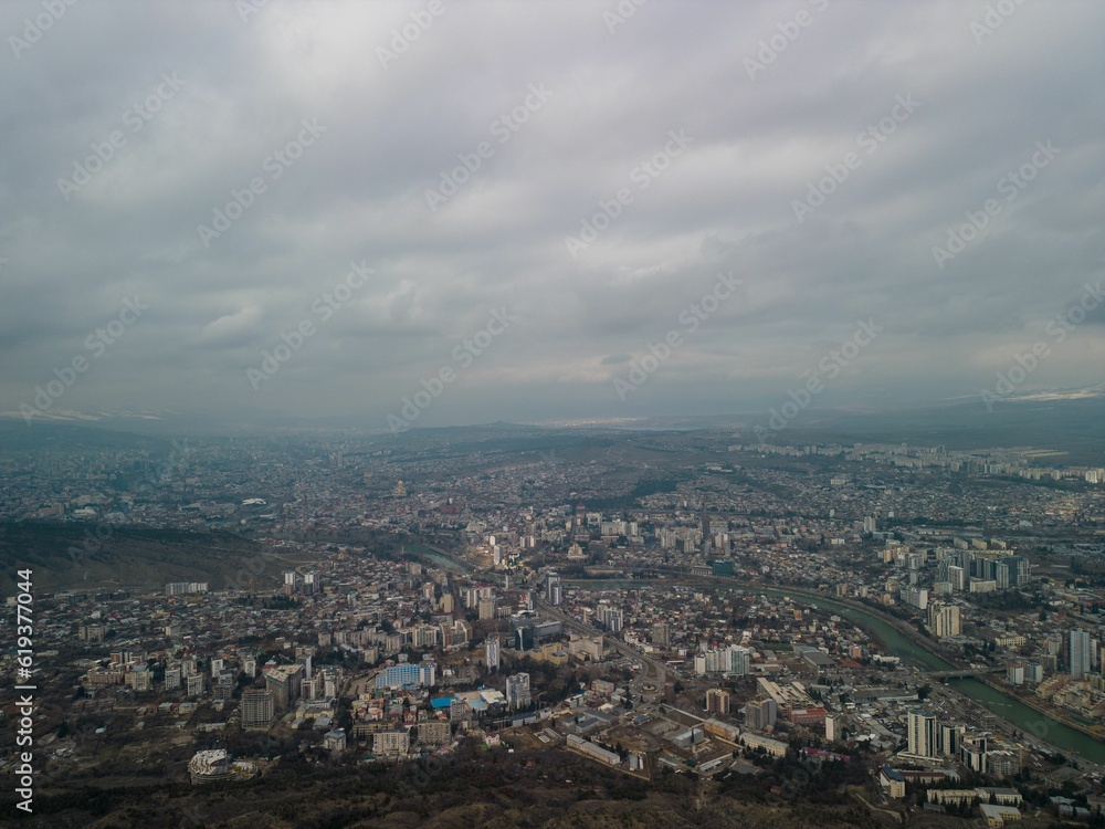 Aerial shot of the cityscape of Tbilisi, Georgia with buildings against a clouded sky