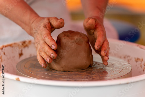 Close-up of a woman's hands beautifully and smoothly forming a brown clay vase on a potter's wheel.