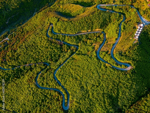 Aerial shot of a winding road surrounded by a lush green forest. Signagi, Georgia. photo