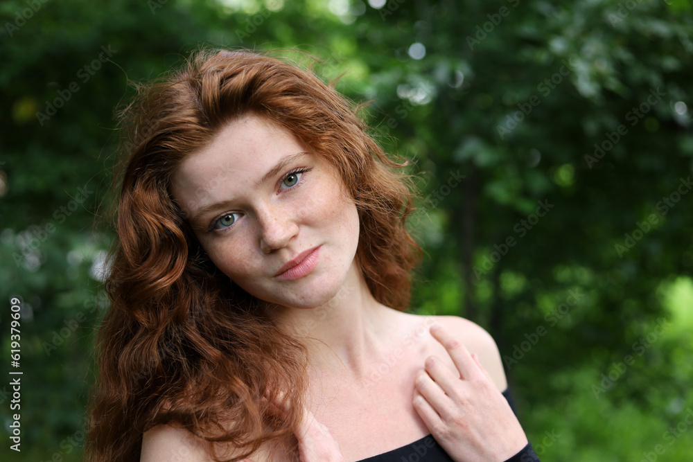 Portrait of smiling ginger girl with long red hair and freckles in summer park. Young sensual model, natural female beauty Portrait of smiling ginger girl with long red hair and freckles in summer park. Young sensual model, natural female beauty