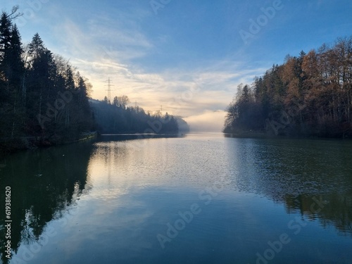 Scenic landscape with a tranquil lake surrounded by lush woodland in a peaceful morning light