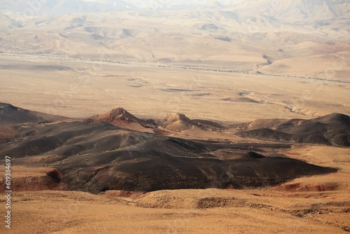 A crater in a desert with its dark hills and bright sand