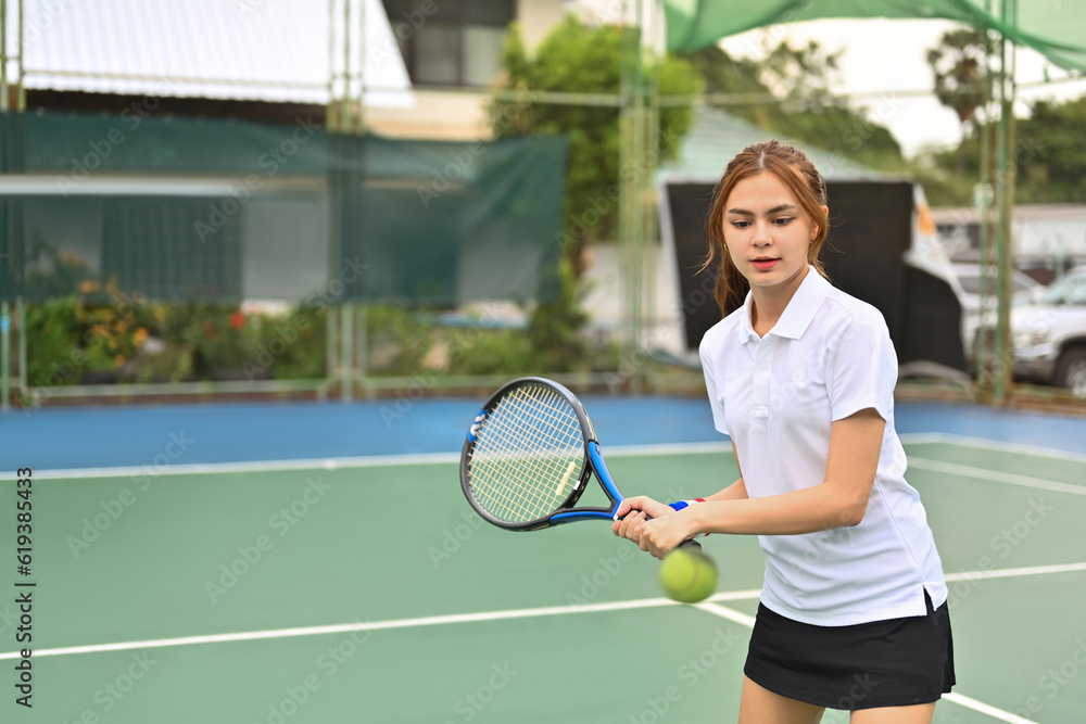 Sportive young woman with racket returning a ball at the tennis court. Sport, fitness, training and active life concept