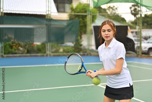 Sportive young woman with racket returning a ball at the tennis court. Sport, fitness, training and active life concept © Prathankarnpap