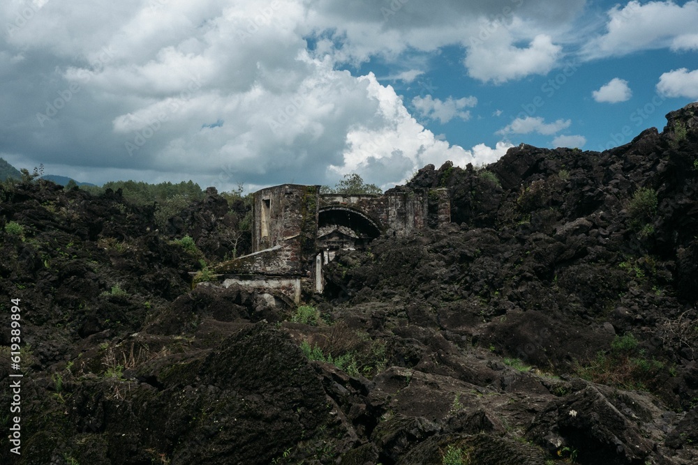 Low-angle of a ruined, old building on the hillside with cloudy sky background