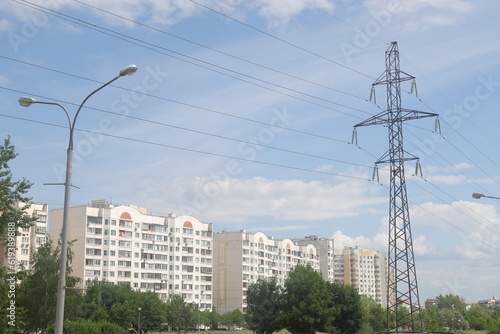 High voltage power lines and pylons in the city. Power lines against the background of residential buildings, ecology.