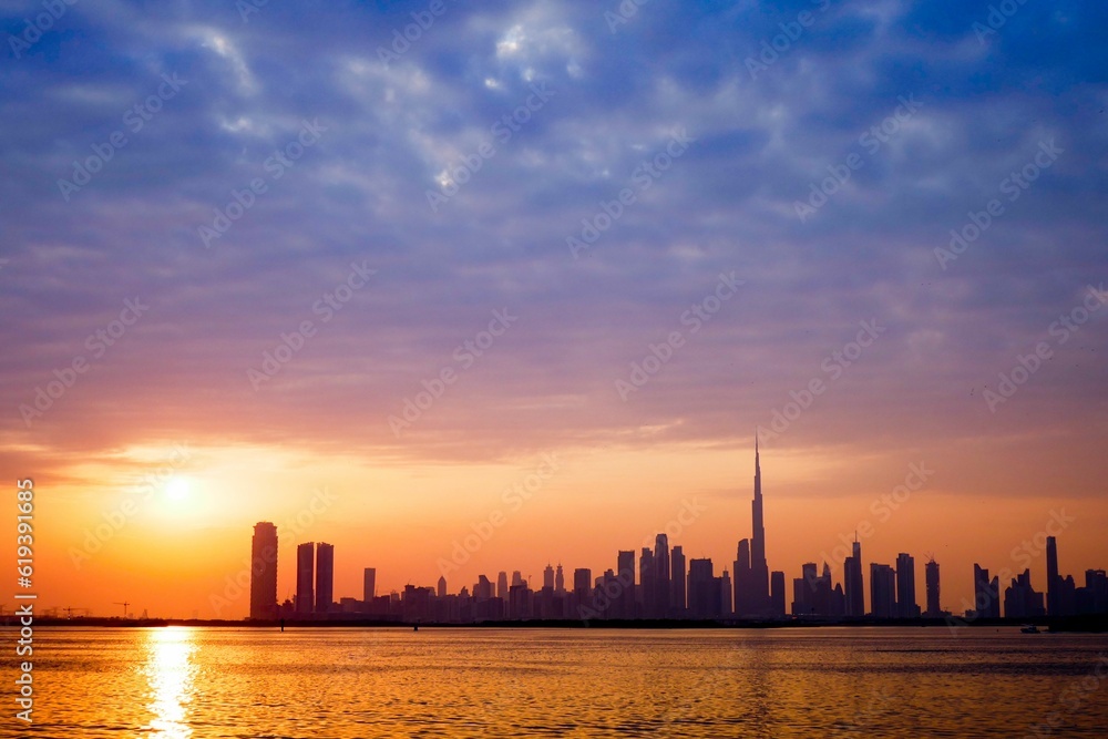 Scenic sunset above a tranquil beach with the Dubai skyline in the background on a summer day