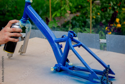 the father paints the child's bicycle with blue paint. photo