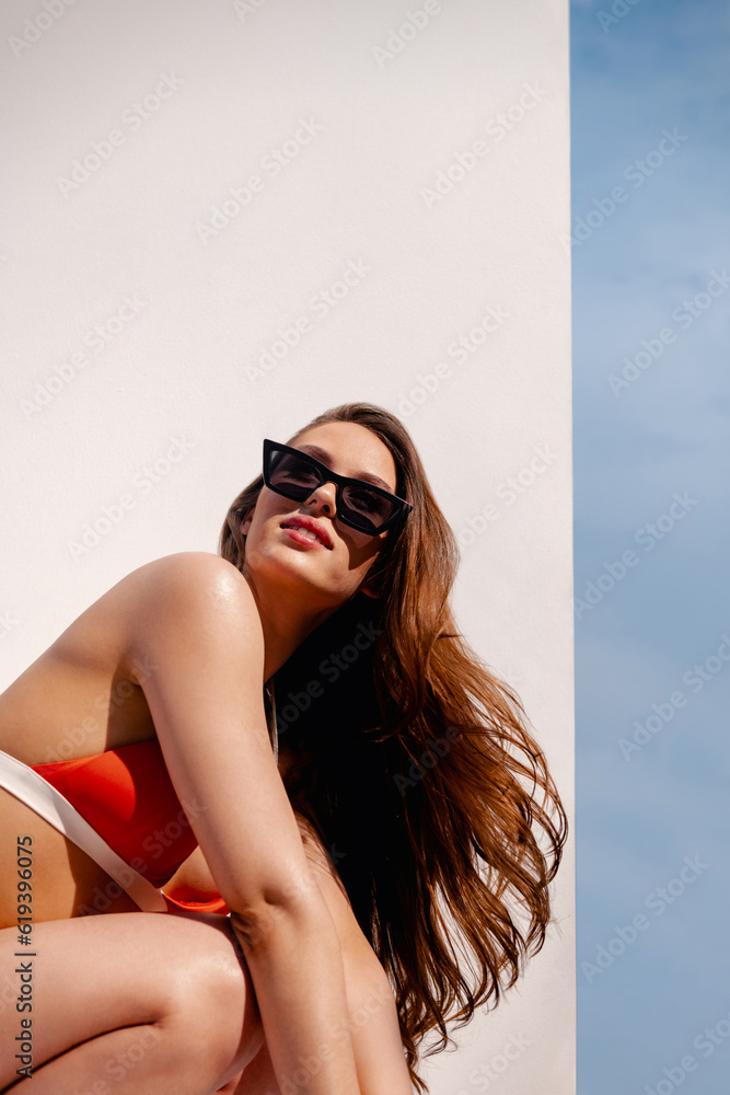 Beautiful woman in bikini enjoying sunbathing while relaxing against white background outdoors Beautiful woman in bikini enjoying sunbathing while relaxing against white background outdoors