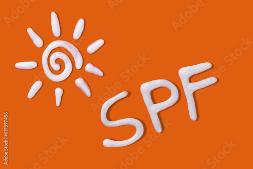 SPF cream. Sunscreen cream in a sun shape on orange background. Creative idea of suntan lotion cream. Sun ultraviolet protection concept.