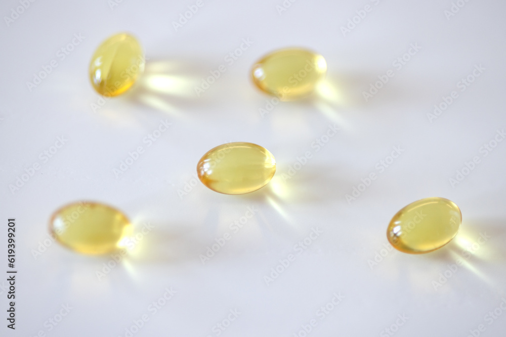 Five yellow gelatin capsules on a white table Five yellow gelatin capsules on a white table
