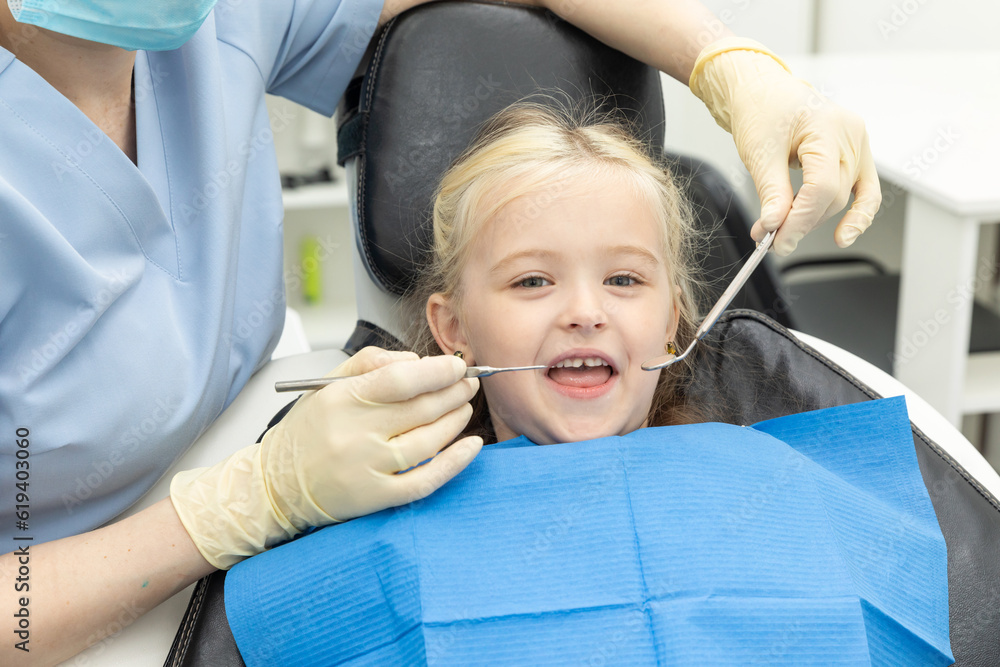 Pediatric dentist examines condition of teeth and braces in child girl. Pediatric dentist examines condition of teeth and braces in child girl.