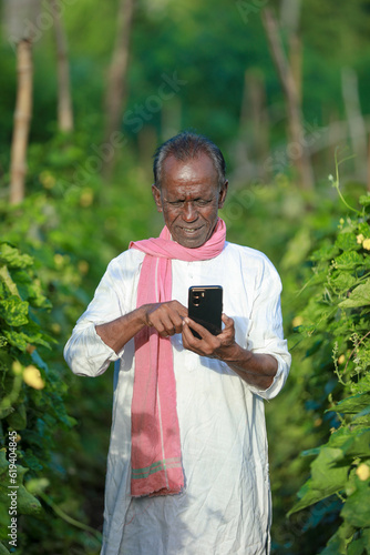 Indian farming, farmer holding bottle gourd, happy farmer speaking on cell phone