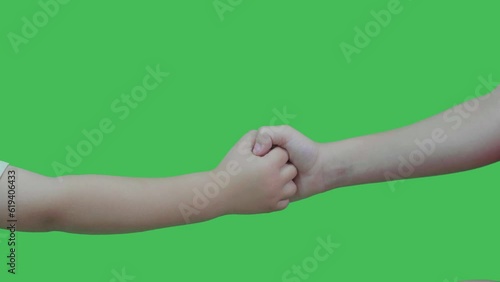 two children shaking hands in green chroma