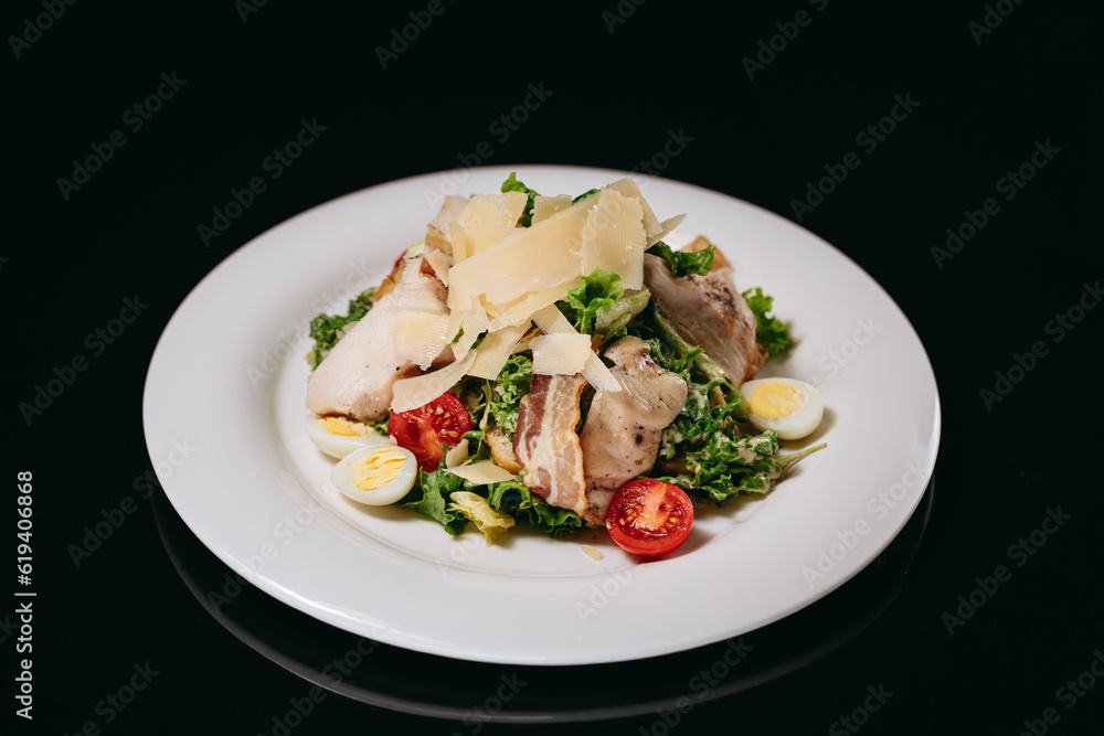 Caesar salad with chicken on a black background Caesar salad with chicken on a black background