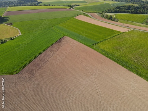 Aerial view of agriculture fields with green growing crop and plowed soil in spring 