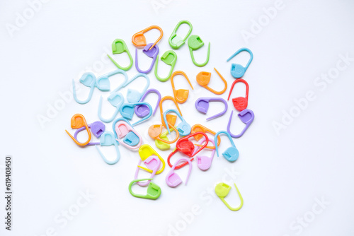 Many colorful plastic knitting markers on a white background.