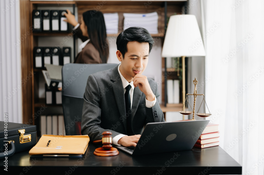 Fototapeta premium Asian lawyer man working with a laptop and tablet in a law office. Legal and legal service concept. Looking at camera in modern office.