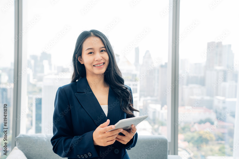 Fototapeta premium Shot of elegant young business woman smiling and using tablet while walking in the office. 