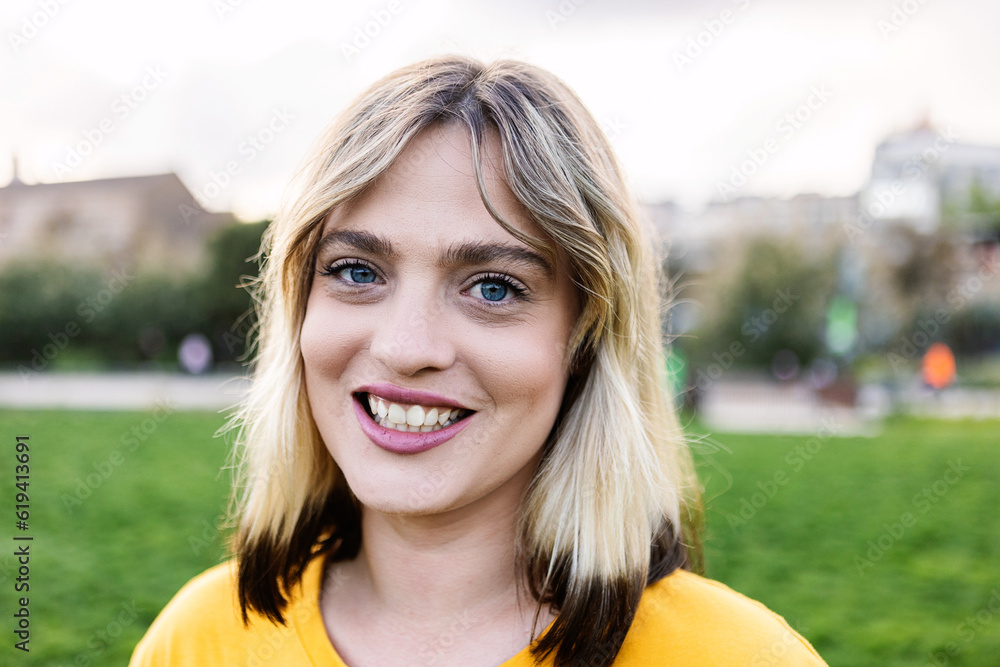 Outside portrait of young trendy blonde woman looking at camera at city park. People concept. Outside portrait of young trendy blonde woman looking at camera at city park. People concept.