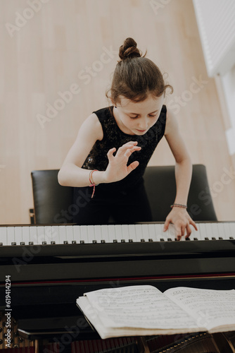 Elegantes Mädchen sitzt am Konzertflügel und spielt Klavier  photo