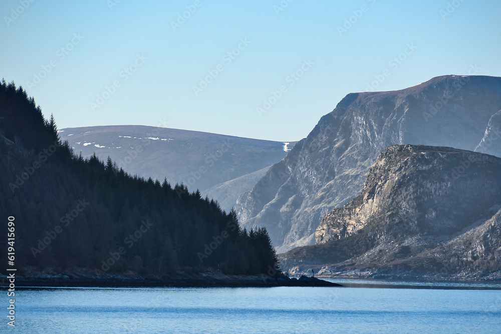 Fjord with mountains on horizon. Water glistens in the sun in Norway. Landscape