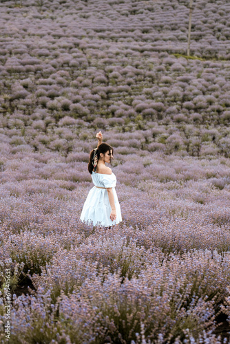 Young woman in a white dress posing in a lavender field.The concept of a photo shoot in lavenders