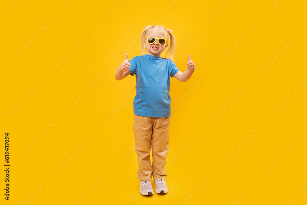Full-leight portrait of girl in blue T-shirt and sunglasses showing thumbs up. Copy space, mock up Full-leight portrait of girl in blue T-shirt and sunglasses showing thumbs up. Copy space, mock up