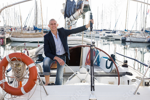 European man in jeans and a jacket posing on yacht in port © caftor