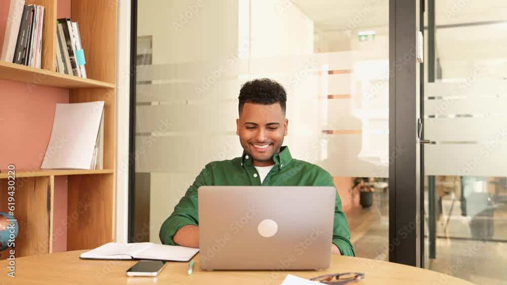 Successful freelancer. Happy millennial Indian man sitting at desk with laptop, smiling and typing, enjoying remote work, male student studying on the distance Successful freelancer. Happy millennial Indian man sitting at desk with laptop, smiling and typing, enjoying remote work, male student studying on the distance