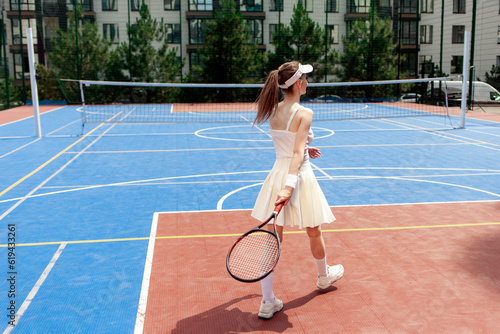 girl tennis player in white uniform holding racket on tennis court, female athlete playing tennis outdoors © Богдан Маліцький