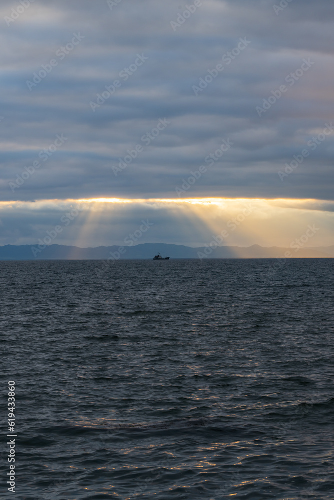 Sunset over the sea with dramatic clouds and rays of light.