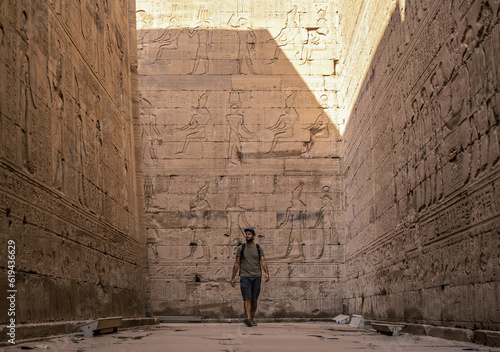 A young tourist visiting the beautiful temple of Edfu in the city of Edfu, Egypt. On the bank of the Nile river, geco-Roman construction, temple dedicated to Huros