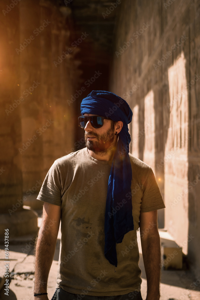 A young tourist in a blue turban visiting the Edfu Temple in the morning near Aswan city. Egypt, west bank of the nile in the city of Edfu, Greco-Roman construction, dedicated to Horus