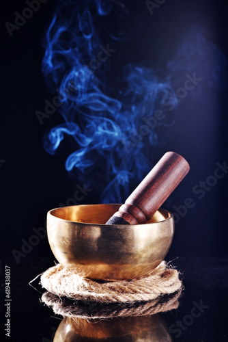 Tibetan singing bowl with stick on the black background 