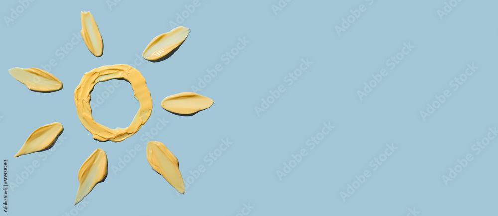 Cosmetic smear of cream texture in the form of a yellow sun on a blue background. Sunscreen cream. Copy space. Cosmetic smear of cream texture in the form of a yellow sun on a blue background. Sunscreen cream. Copy space.