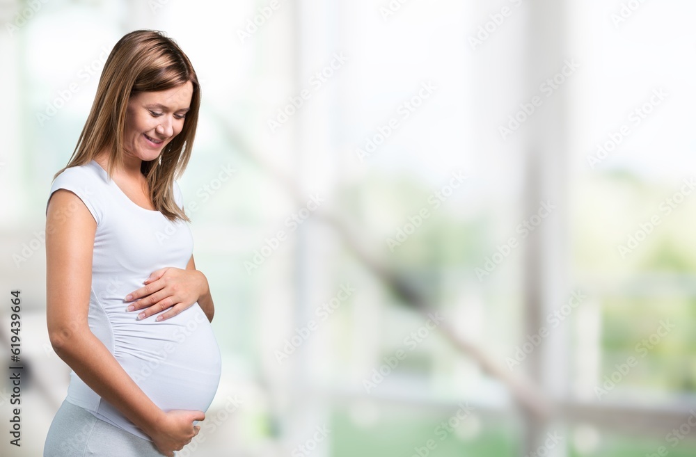 Portrait of young happy pregnant woman holding her belly