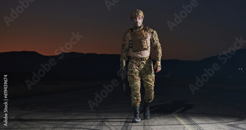A professional soldier in full military gear striding through the dark night as he embarks on a perilous military mission