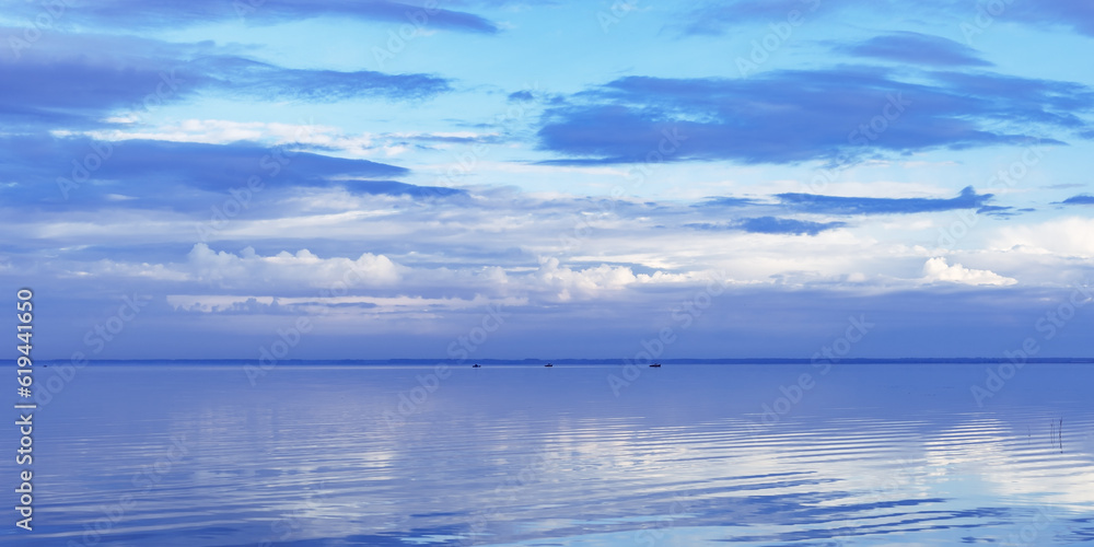 Beautiful white blue clouds over lake, natural environment banner, symmetric sky background, cloudscape on lake. Nature abstract, cloudy sky reflected on water, calm windless weather, peaceful