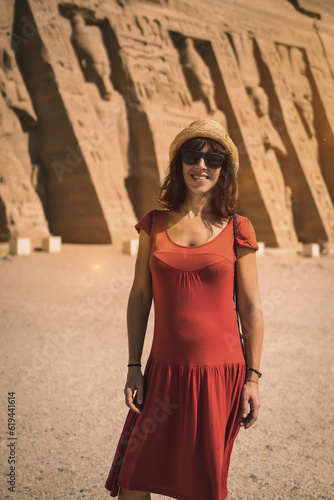 Portrait of a young tourist in red dress visiting the Temple of Nefertari near Abu Simbel in southern Egypt in Nubia next to Lake Nasser. Temple of Pharaoh Ramses II, travel lifestyle © unai