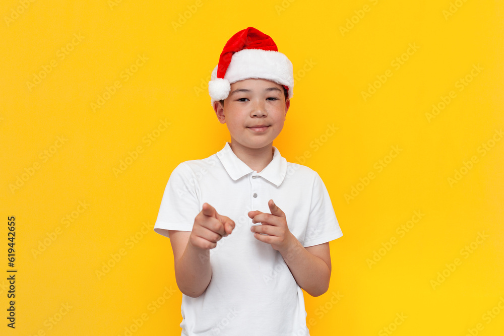 I choose you. little asian boy in santa hat points at you on yellow isolated background, korean child in new year's hat I choose you. little asian boy in santa hat points at you on yellow isolated background, korean child in new year's hat