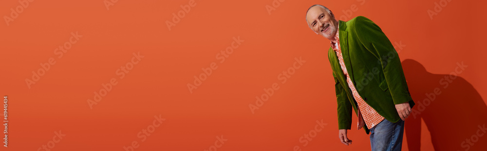 full length of delighted senior model in trendy casual clothes smiling at camera on red orange background with shadow, green velour blazer, personal style, happy aging concept, banner