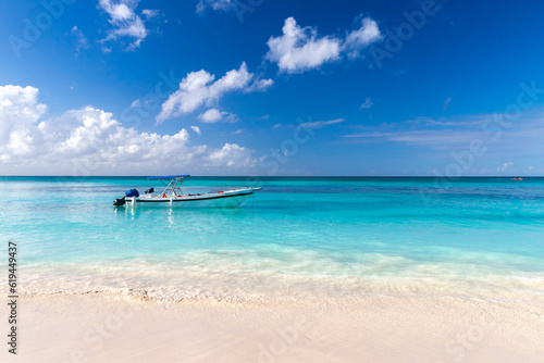 Coastal Caribbean landscape with fishing boat anchored near empty sandy beach © evannovostro